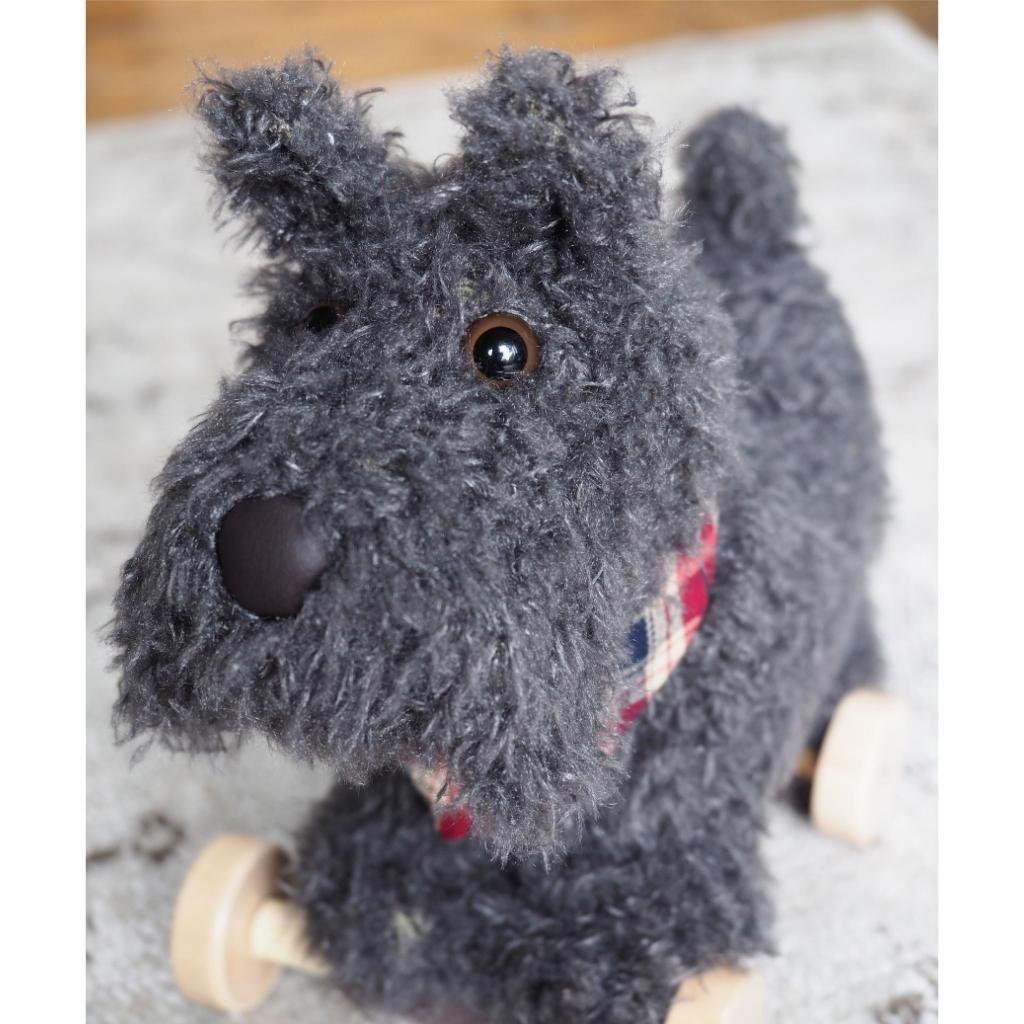 close up of soft toy pull along scottie dog with grey fur and a plaid neckerchief