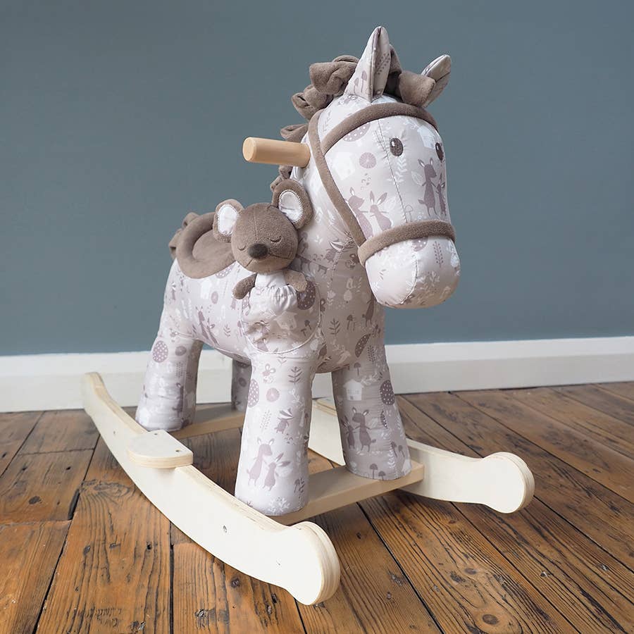 a cute fabric horse with brown bridle, saddle, mane and tail on wooden rockers with a soft toy mouse in a pocket on its shoulder in a room setting