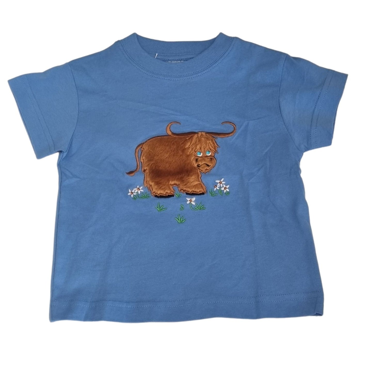 The Ramblers Highland Cow Embroidered T Shirt MacMoo Design for children is a blue, short-sleeved 100% cotton tee featuring a fuzzy brown highland cow on grass with white flowers, offering all-day comfort.