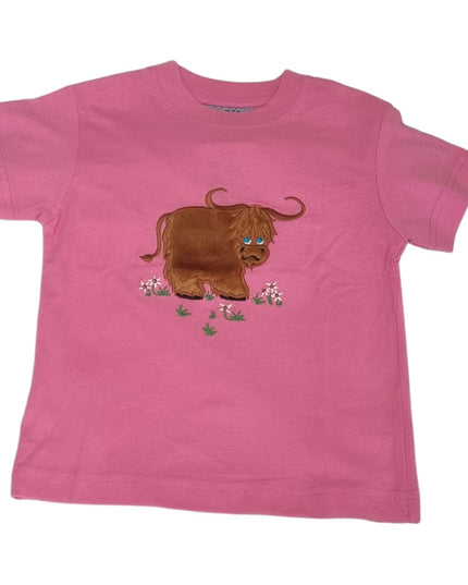 The Ramblers Highland Cow Embroidered T Shirt MacMoo Design features a brown highland cow among pink and green flowers, embroidered on 100% cotton pink fabric, perfect for children.