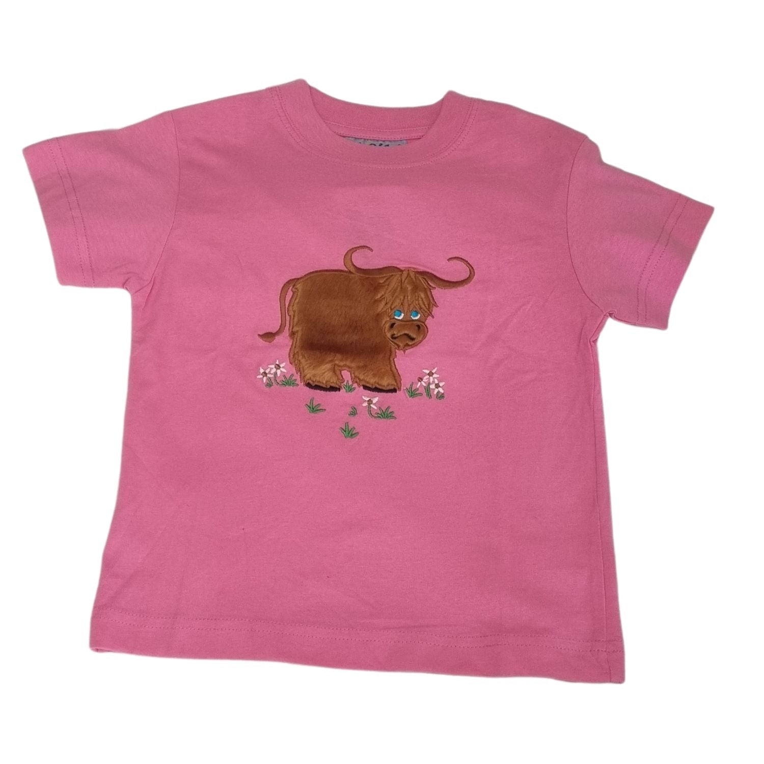 The Ramblers Highland Cow Embroidered T Shirt MacMoo Design features a brown highland cow among pink and green flowers, embroidered on 100% cotton pink fabric, perfect for children.