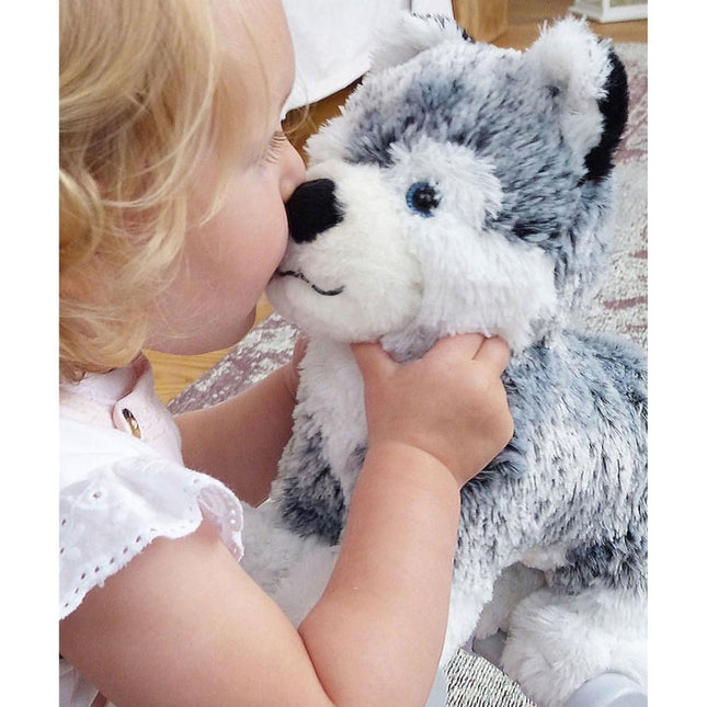 a baby girl kissing a silver and white soft toy husky dog on the nose
