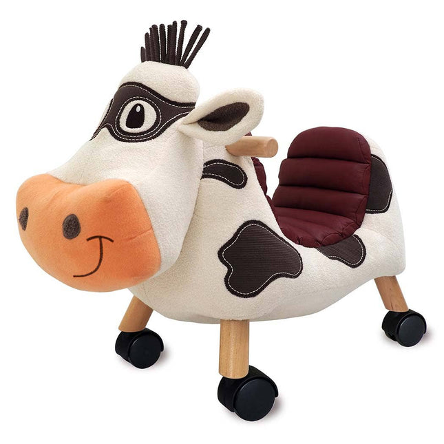 The Moobert Cow Ride On Toy by Little Bird Told Me UK is a plush, wooden ride-on with a padded seat, brown spots, sturdy legs, and black wheels—ideal for encouraging toddler development through active play.