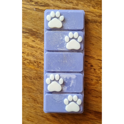 the top view of a blue wax melt bar with white paw prints on a wooden table