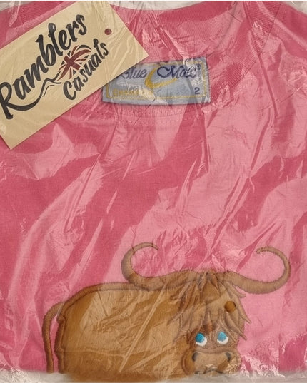 A folded pink 100% cotton childrens T-shirt, featuring a cartoon Highland cow MacMoo embroidery, is shown in clear packaging with a Ramblers tag and a Blue Max size 2 collar label.
