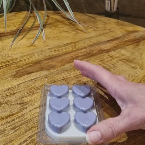 a wax melt bar with hearts in a clamshell is removed from the clamshell and shown close up