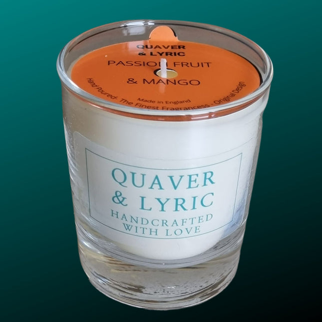 a candle in a glass with quaver & lyric handcrafted with love label and orange dust cover on a teal background