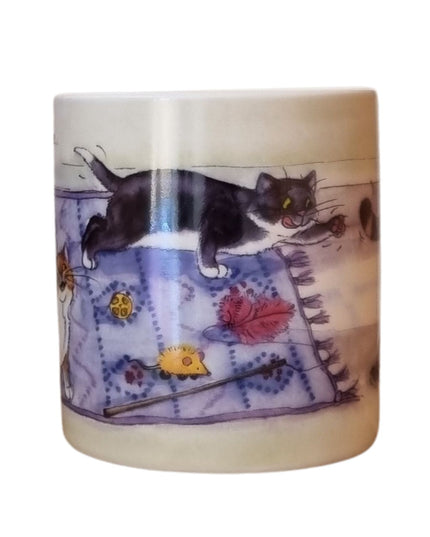 The Alisons Animals Cat Mug features a cartoon of a black and white cat with toys on a purple rug. Gift boxed, it’s perfect for cat lovers and showcases Alison Lingleys charming artwork.