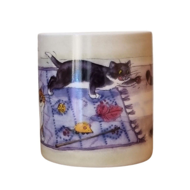 The Alisons Animals Cat Mug features a cartoon of a black and white cat with toys on a purple rug. Gift boxed, it’s perfect for cat lovers and showcases Alison Lingleys charming artwork.