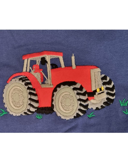 The Ramblers Tractor T Shirt Embroidered Blue for Children features a red tractor with large black and gray wheels on 100% blue cotton, accented by small green grass patches.