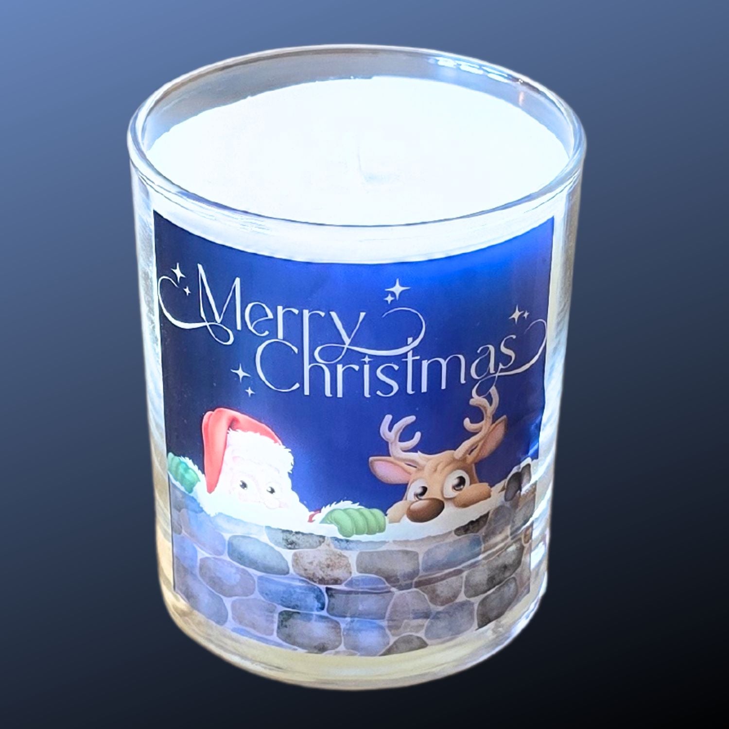 A Christmas scented candles with a charming Merry Christmas design featuring Father Christmas and a reindeer peeping over a wall.