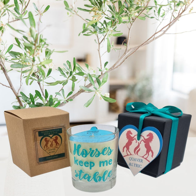 The Quaver&Lyric Scented Candle In Glass Container features the phrase Horses keep me stable and comes with a brown box labeled Handcrafted, a teal ribbon-tied black gift box, and heart tagâ€”perfect for horse lovers.