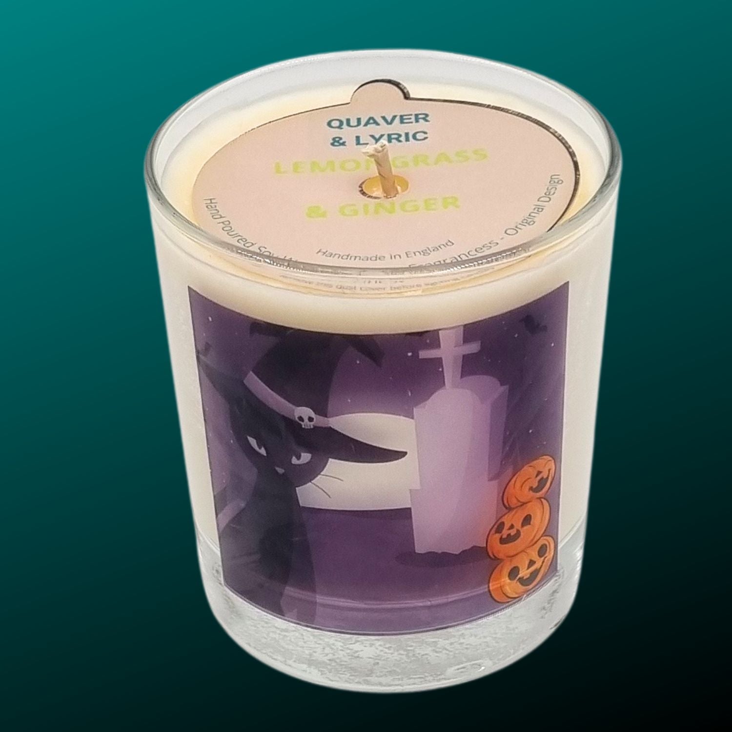 glass container halloween candle with black cat in witches hat in a graveyard with pumpkins