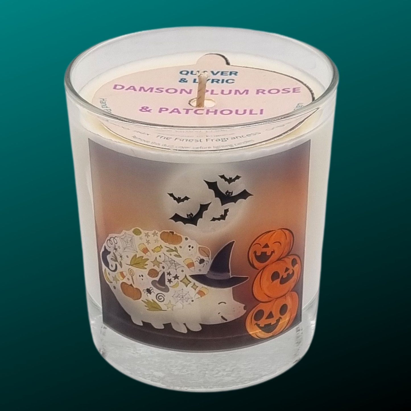 a scented halloween candle in glass with a cute hedgehog in a witches hat with pumkins and bats