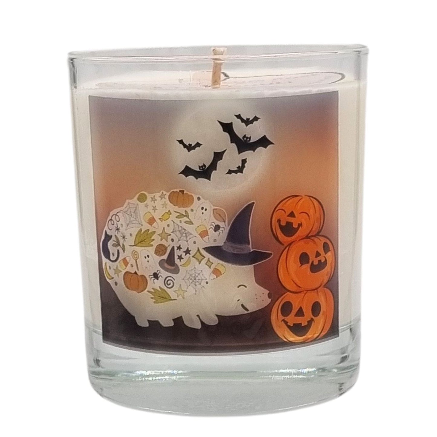 a scented halloween candle in glass with a cute hedgehog in a witches hat with pumkins and bats