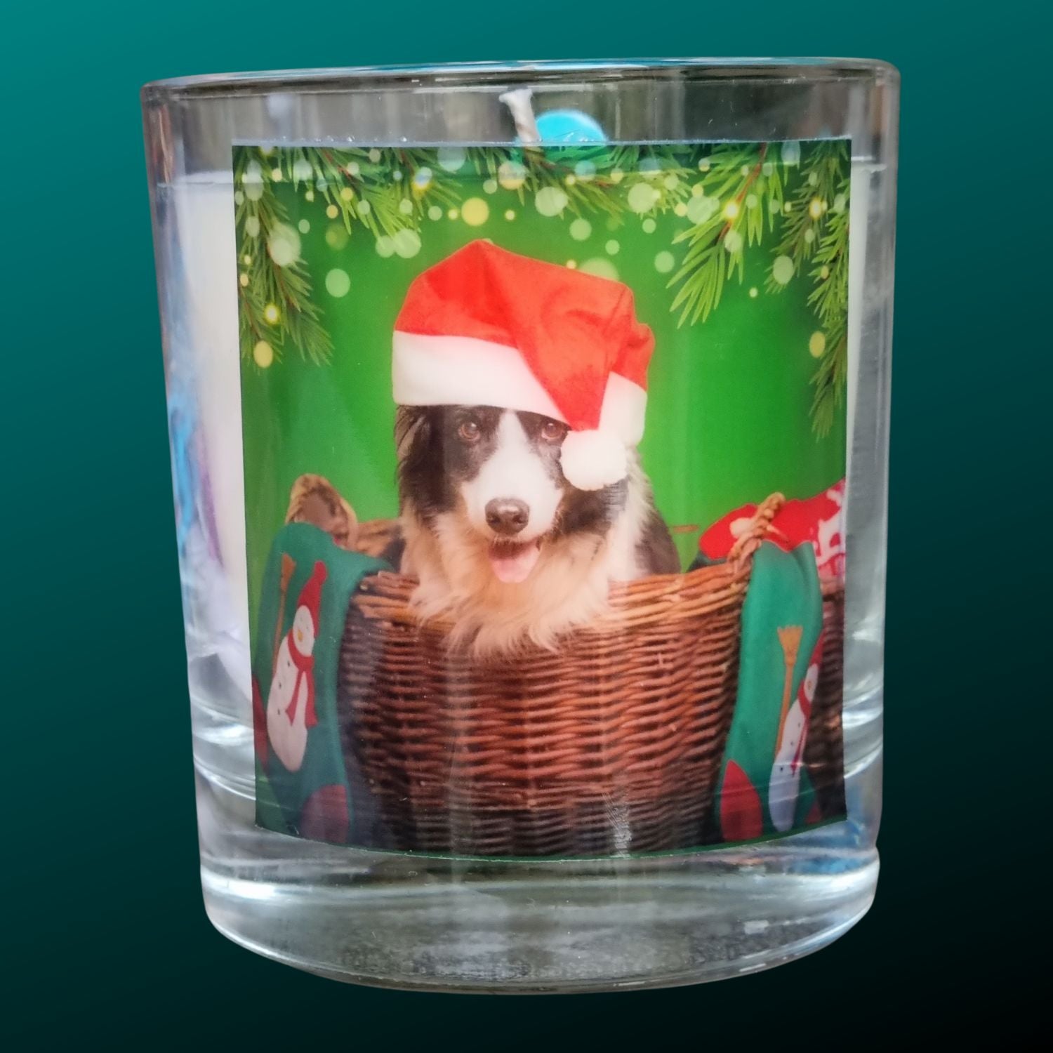 a christmas scented candle in a glass container with a seasonal collie dog in a santa hat design