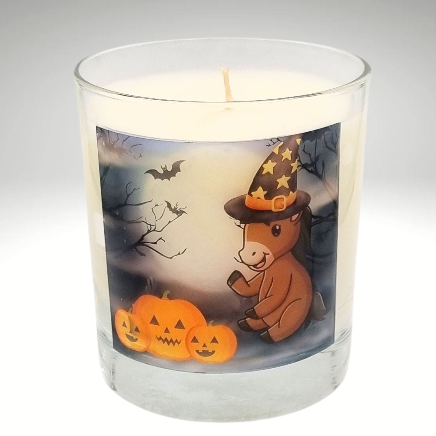 a scented Halloween candle in a glass container with a cute cartoon pony and pumpkin design