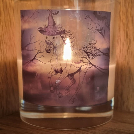 a lit scented halloween candle featuring a spooky galloping horse design