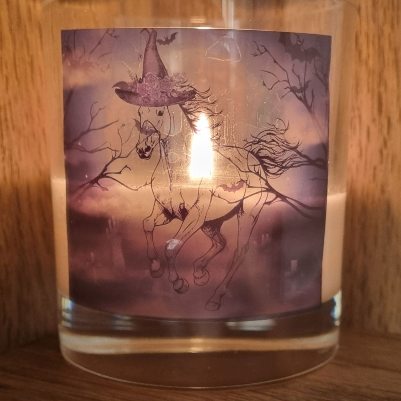a lit scented halloween candle featuring a spooky galloping horse design