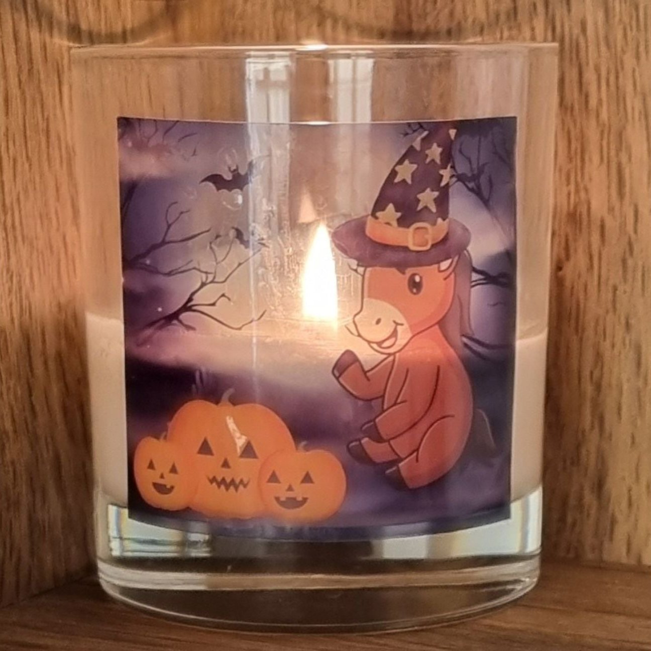 a lit scented halloween candle with a cute cartoon pony and pumpkin design