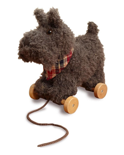 a soft toy scottie dog on wheels with grey fur and a plaid neckerchief