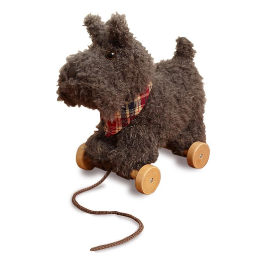 a soft toy scottie dog on wheels with grey fur and a plaid neckerchief