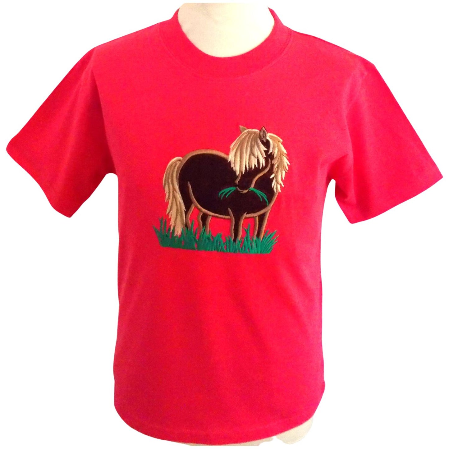 A fuschia pink short sleeve, round necked T-shirt featuring an embroidered design of a brown shetland pony with a cream mane and tail eating a mouthful of grass