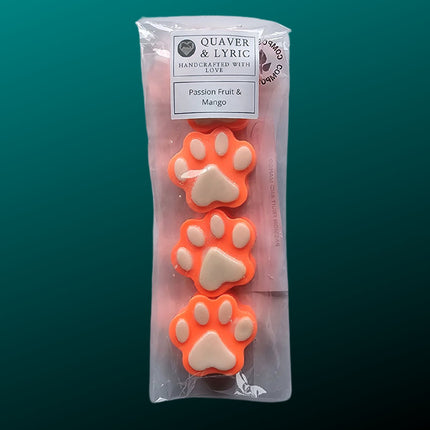 four orange paw shaped wax melts with white paw pads in a packet with quaver & lyric  branding