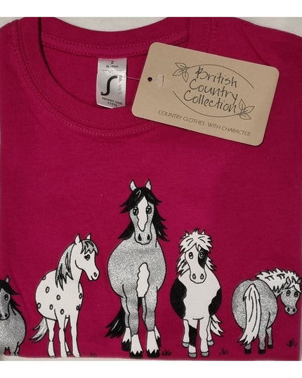 The Childrens T Shirt Printed The Herd Horse Design by British Country Collection is a folded pink 100% cotton tee featuring five uniquely patterned cartoon horses and a beige brand tag. Machine washable for easy care.