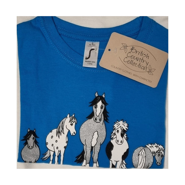 A folded blue Childrens T Shirt Printed The Herd Horse Design by British Country Collection, made from 100% cotton, features cartoon horses on the front and a branded tag attached to the collar.