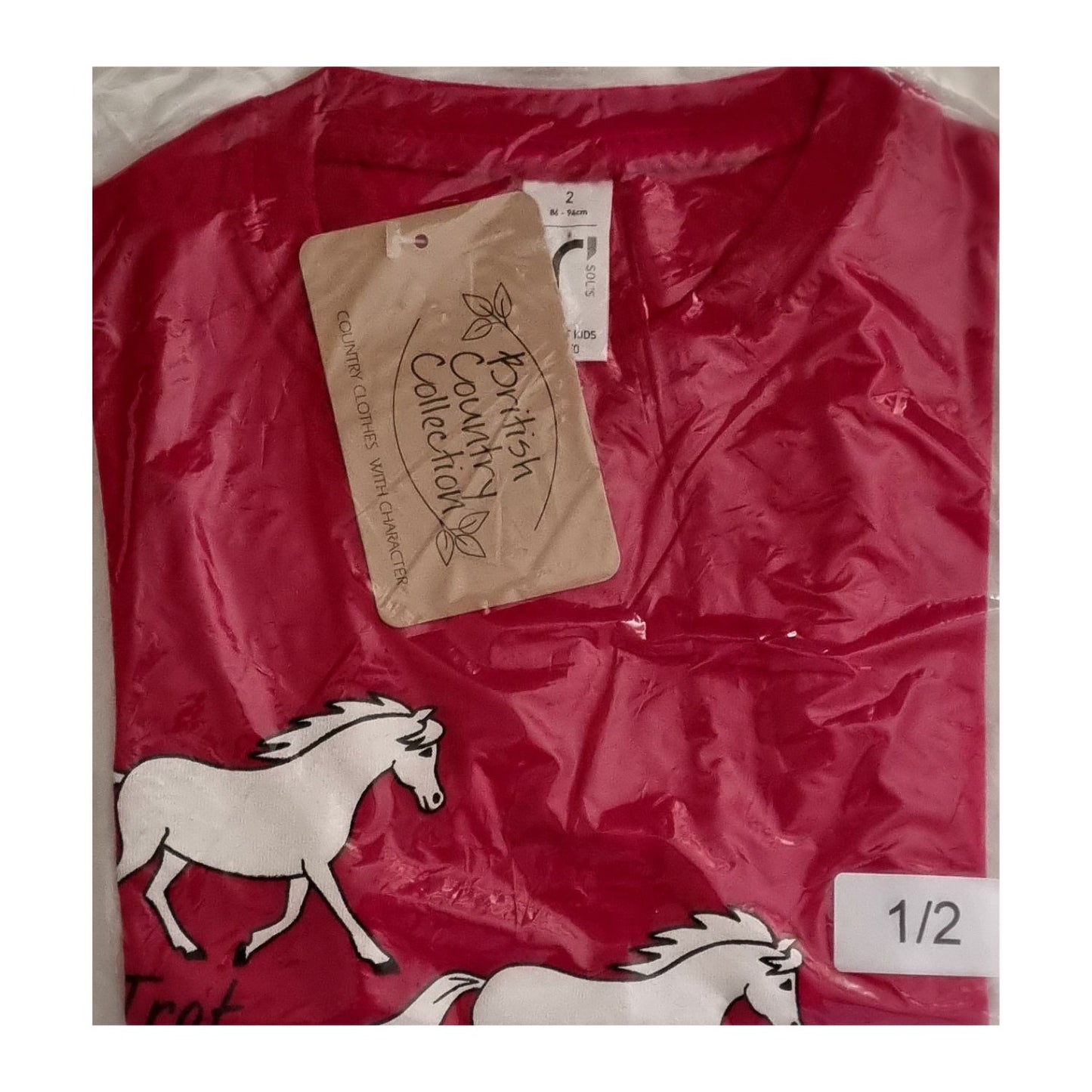 A red British Country Collection Printed Horse T Shirt With Trot, Canter, Jump Design for children is neatly folded in packaging, showing white horse illustrations and labels with the brand and size 1/2.