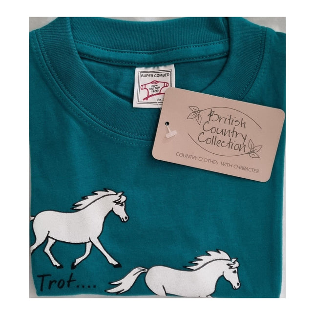 A teal Childrens Printed Horse T Shirt by British Country Collection, featuring white horse illustrations and Trot, Canter, Jump text, is neatly folded. The brand tag near the collar reads British Country Collection.