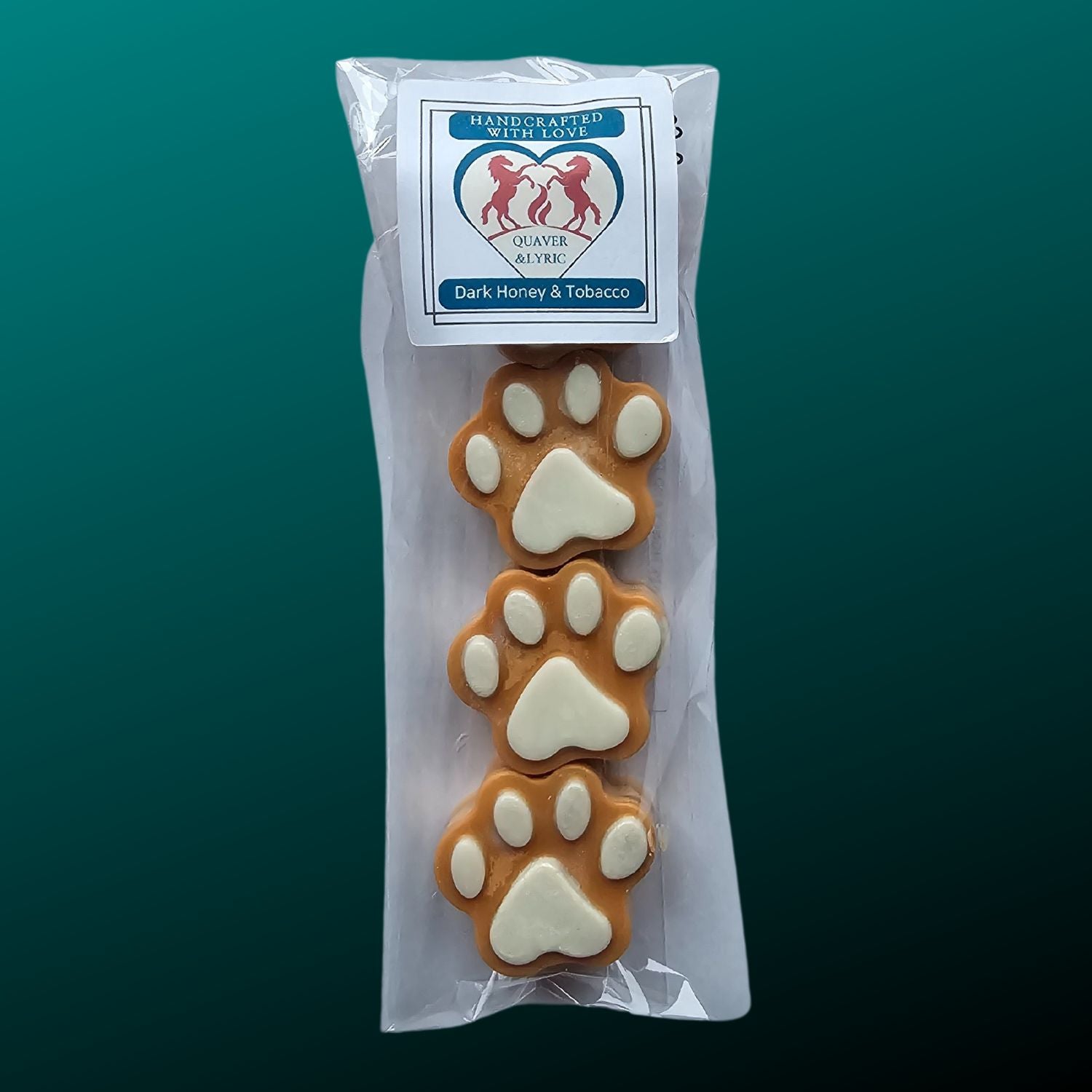 four golden brown paw shaped wax melts with white paw pads in a packet with quaver & lyric rearing horse branding