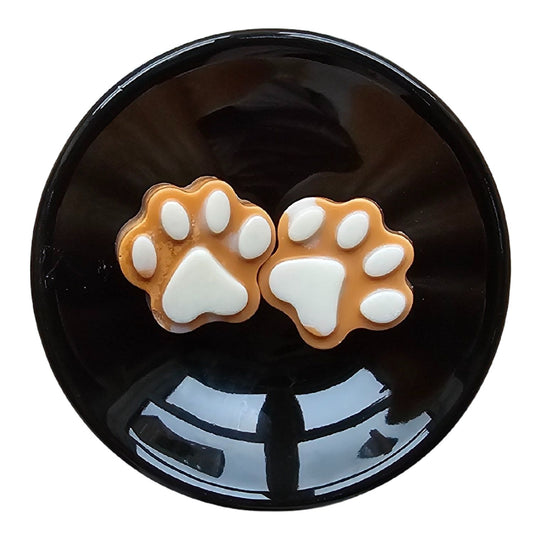 two brown wax melt paws with white paw accents in the top of a black wax melt burner