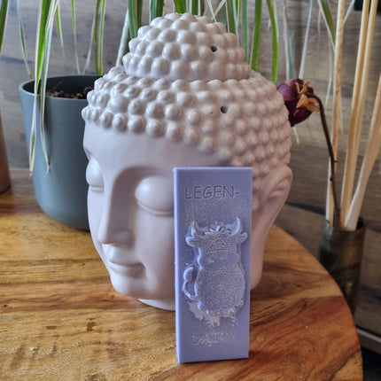 a violet Wax Melt bar with highland cow and writing legen....dairy resting against a buddha head wax warmer