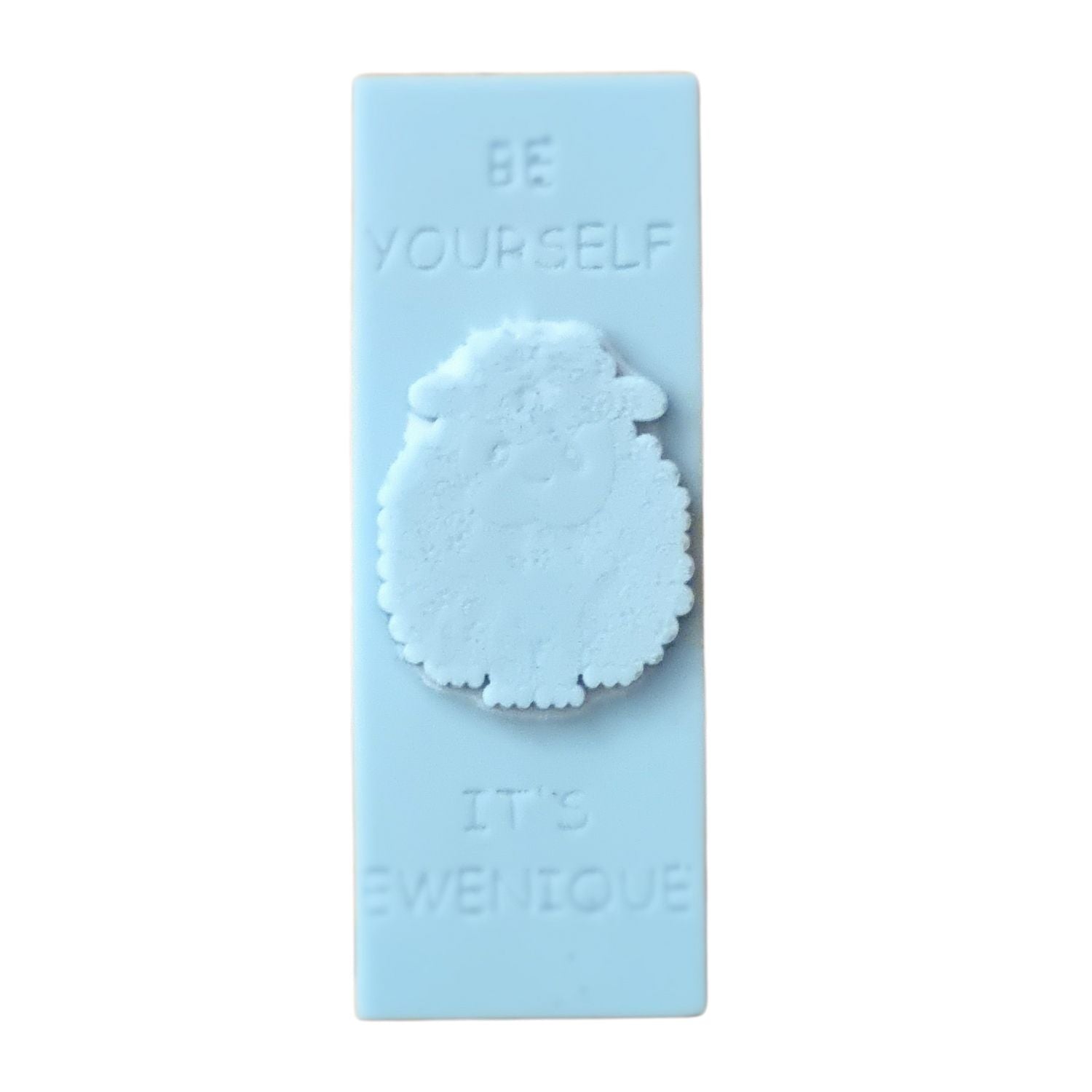 A light blue coloured rectangle of wax with a raised sheep design with the writing be yourself above and it's ewenique below.