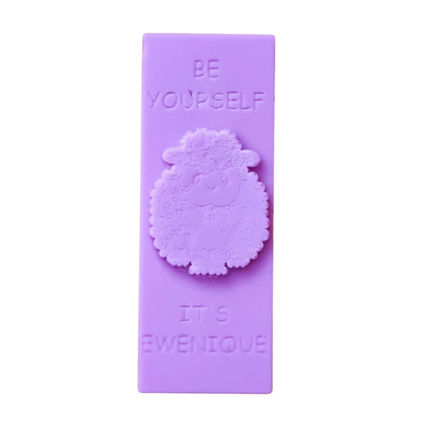 A light indigo coloured rectangle of wax with a raised sheep design with the writing be yourself above and it's ewenique below.