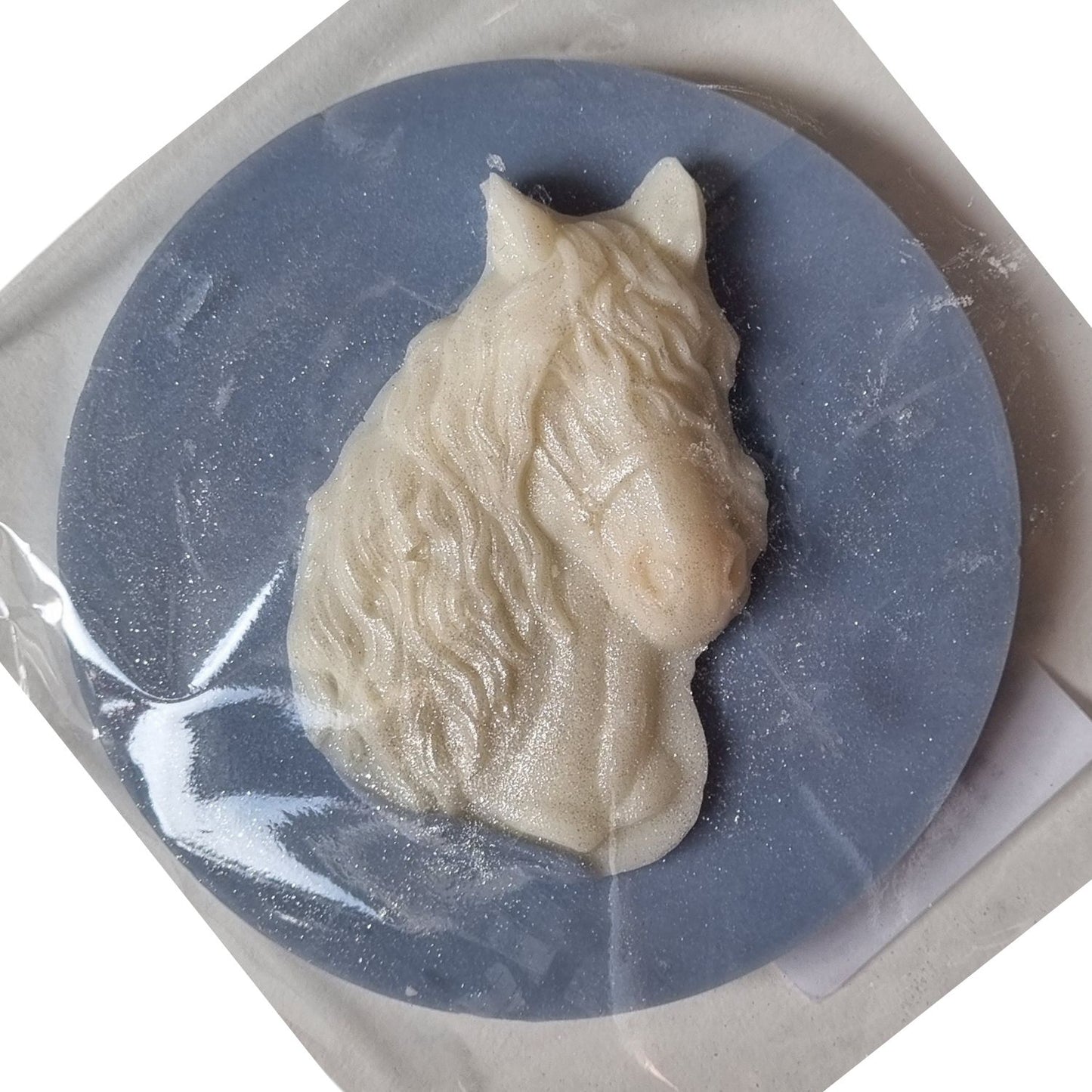 A blue coloured disc shaped wax melt with a white wax horses head with a flowing mane and forelock.