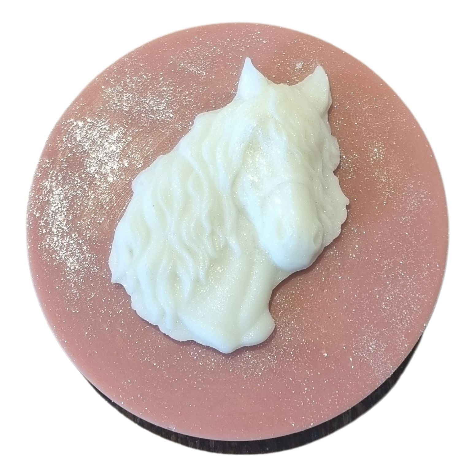 A brown coloured disc shaped wax melt with a white wax horses head with a flowing mane and forelock.