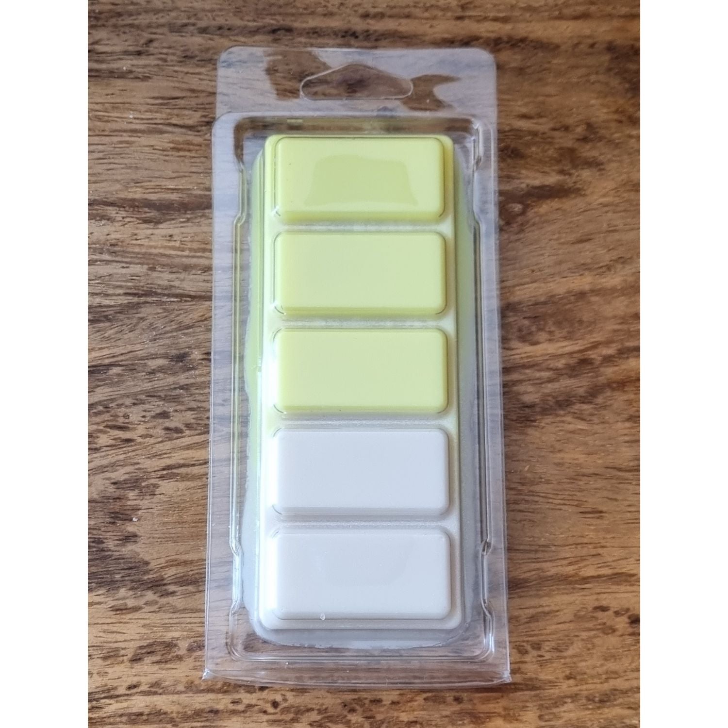  a bright yellow and white wax melt bar in a clamshell 