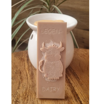 a light brown Wax Melt bar with highland cow and writing legen....dairy resting against a wax warmer