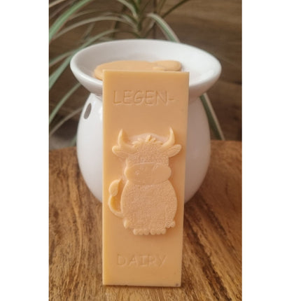 an orange Wax Melt bar with highland cow and writing legen....dairy resting against a wax warmer