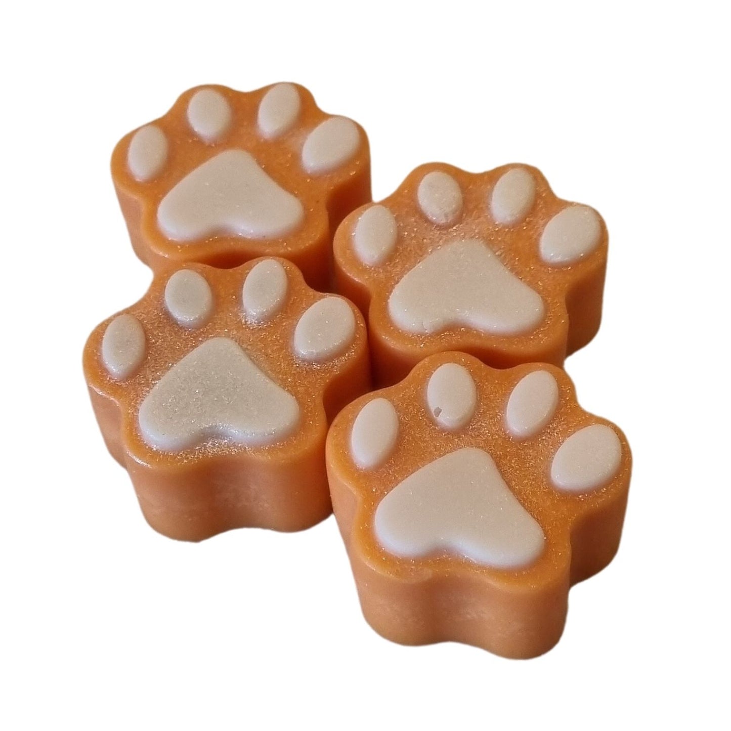 a group of four orange paw shaped wax melts with white paw pads