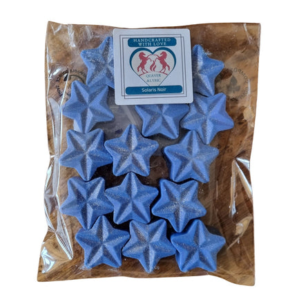 A clear bag labeled Quaver&Lyric holds 15 blue, star-shaped soy wax melts with a hint of shimmer and two unicorns on the packaging. These Soy Wax Melt Stars promise a delightful fragrance and are handcrafted with care.