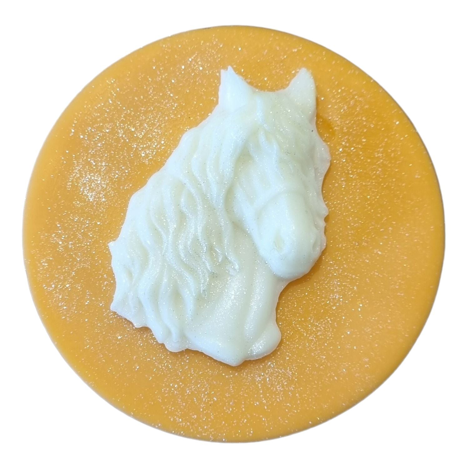 An orange coloured disc shaped wax melt with a white wax horses head with a flowing mane and forelock.