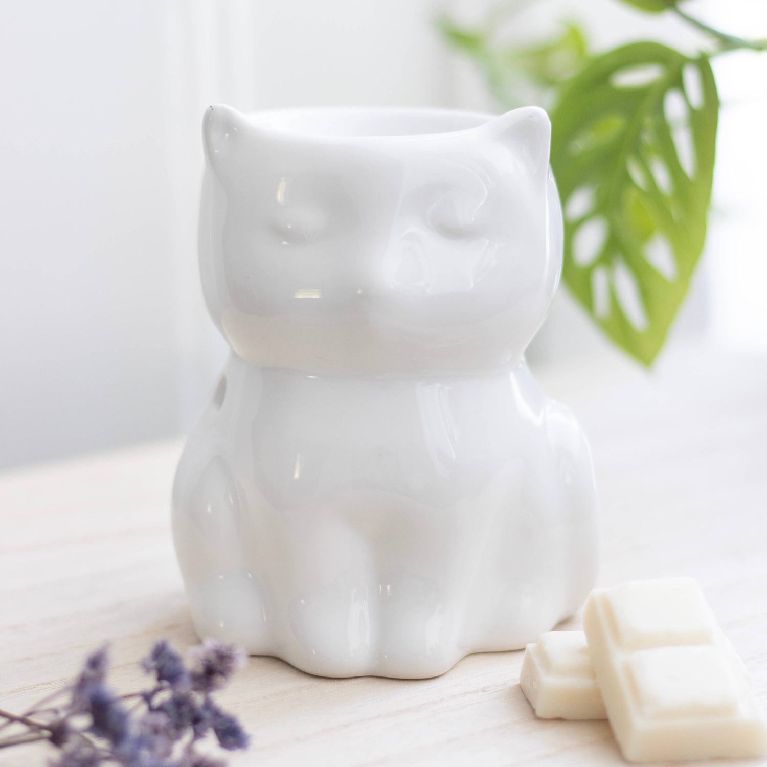a shiny ceramic white cat with lavendar and wax melts