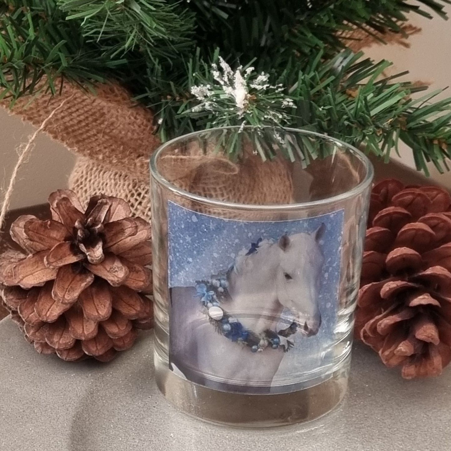 an empty scented candle glass container with a grey horse wearing a festive garland on his neck